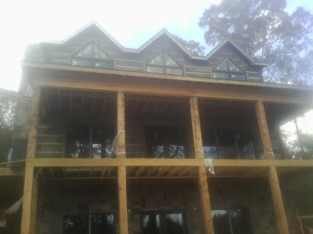 Dormers and porch framing on a large log home under construction — Roof Coating work by our crew in Compton