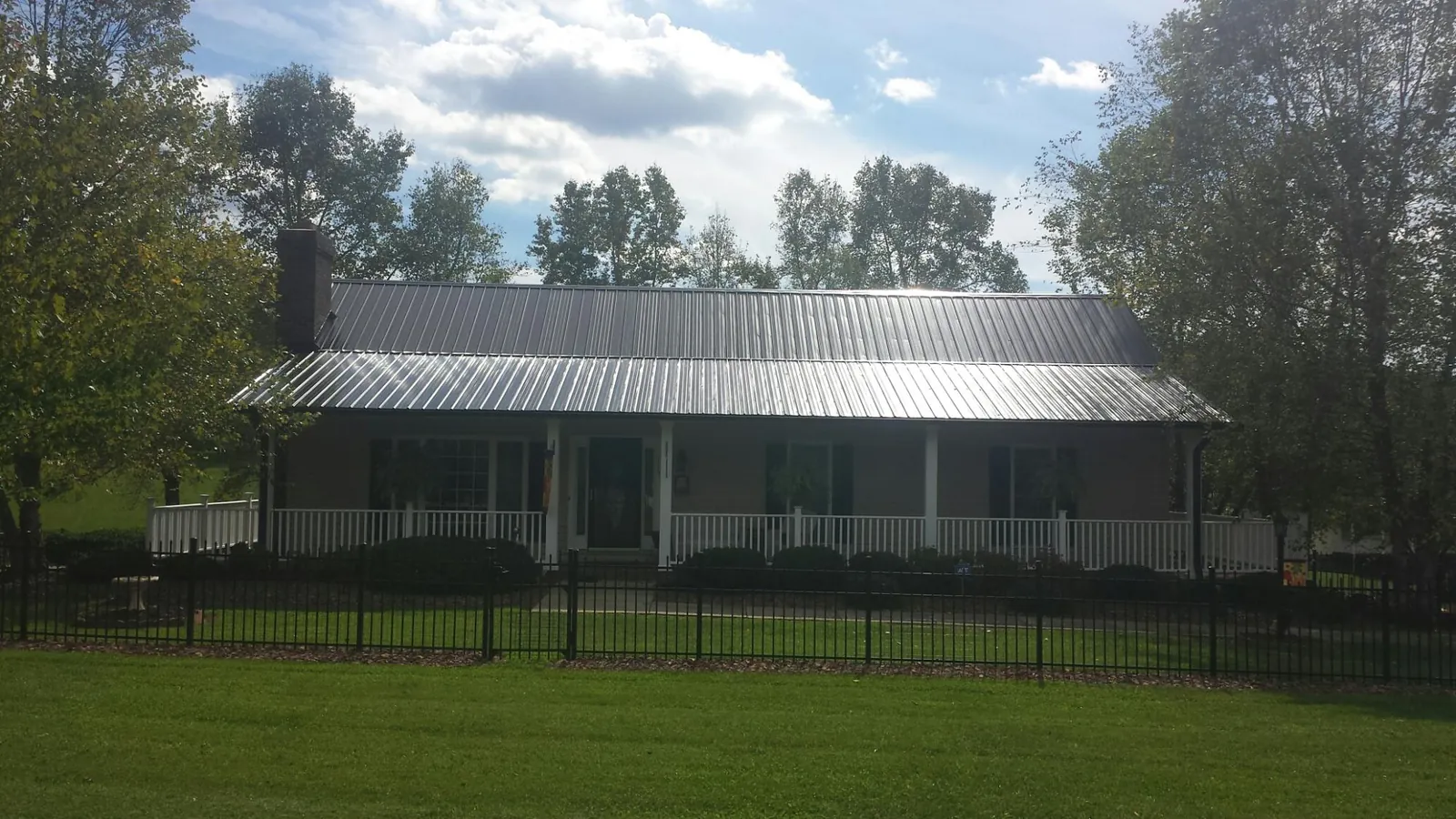 Gray metal roof on a brick ranch with a full width front porch — Gutter Guard Installation work by our crew in Compton