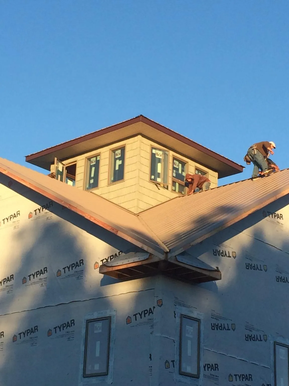 Roofers working around a rooftop cupola on a new metal roof at sunset — Roof Waterproofing in Compton by Roofing Brothers